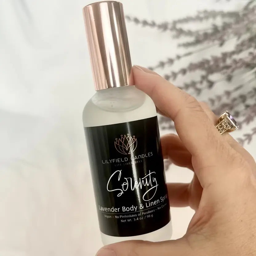 Hand holding Lilyfield Candles Serenity Lavender Body & Linen Spray with floral background